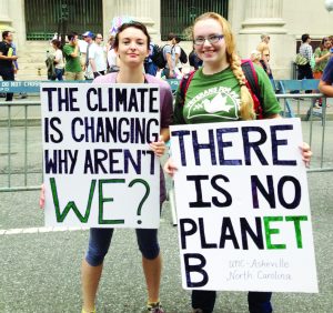 UNCA students Sarah Harrell, left, and Jane Smith, right, hold signs at the People’s Climate March. Photo Illustration by Merry Hughes - Contributor