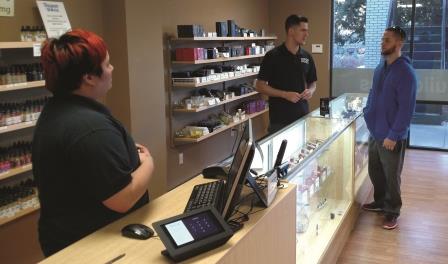 Vapor World manager Christine Ballogdajan and her colleague talk to a customer at the Merrimon Avenue store. (Photo by Lee Elliott)
