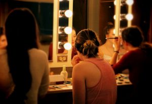 Students prepare makeup for the production