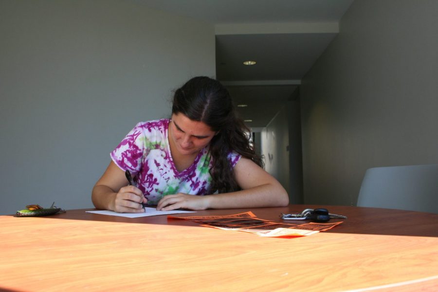 Andrea Genna, environmental studies student from Durham, signs the Real Food Challenge petition. Photo by Megan Suggs.