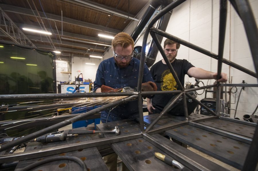 SAE members Justin Turner and Jordan Ellege work of the frame of the electric car. Photo by Nick Haseloff.
