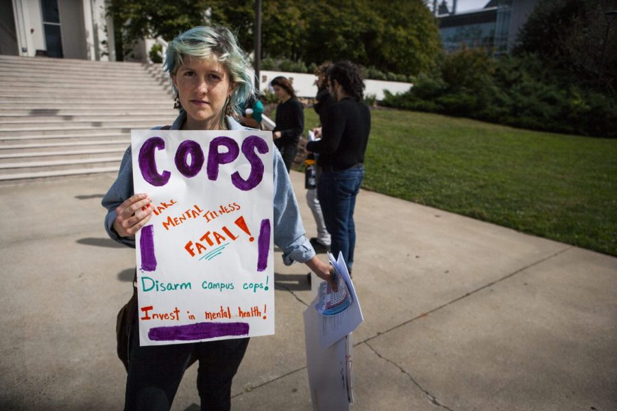 Page Nevel poses with a sign protesting police brutality in front of Ramsey Library on Oct. 16. Photo by Nick Haseloff