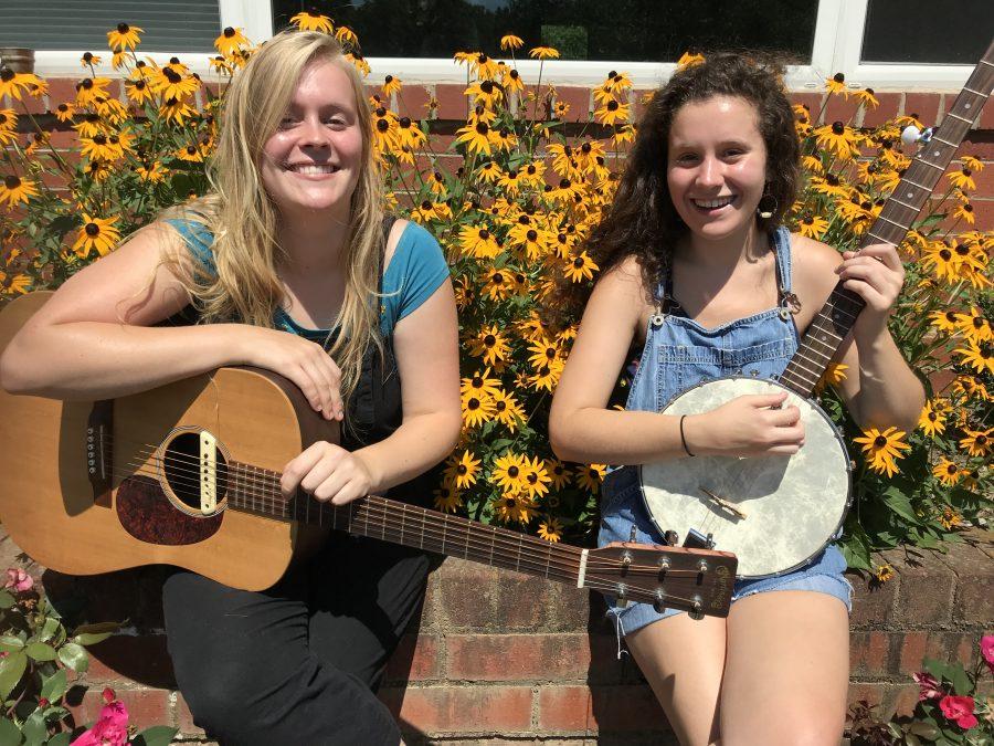 Annie Jo Buchanan (left) and Claire Hoke (right) sit with their signature banjo and guitar that make up their folk sound in Cow Baby. Photo by Taylor Sexton. 