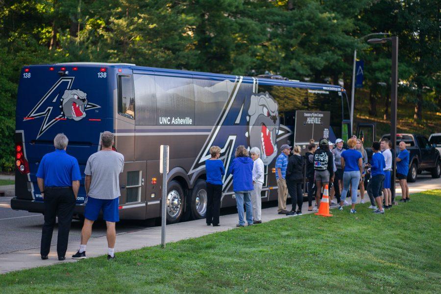 The athletic department gathers around the new wrapped bus, as the soccer team packs up for the maiden voyage to face Navy.