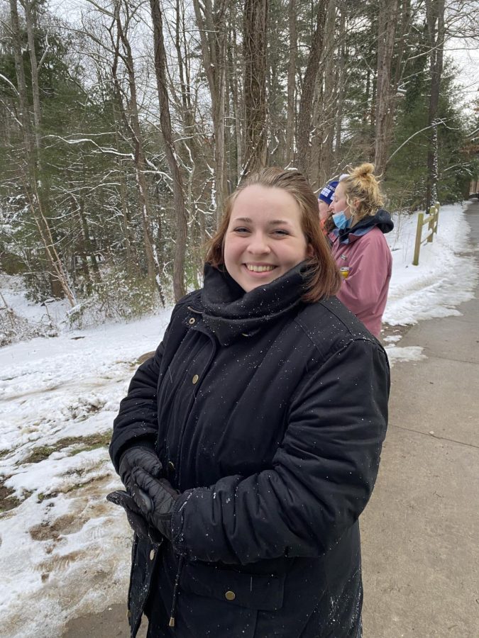 Senior Luna Little smiling as someone sleds down the hill behind the camera.