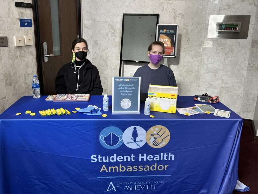  Students Samantha Mazze, left, and Laura Searles sit at a Student Health Ambassador table with COVID resources in Ramsey Library.
