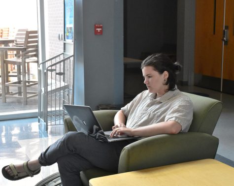 A student studying alone in the lobby of an empty academic building.