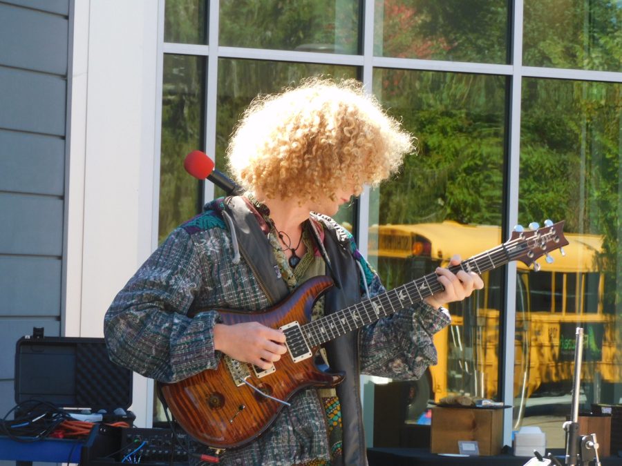 Hadden pictured strumming their guitar during the Live at Lunch performance. 
