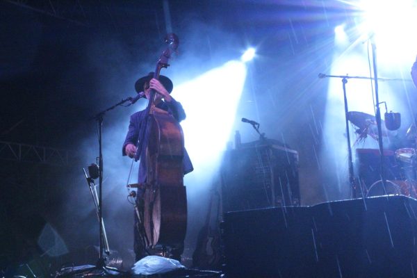 Chris Wood is illuminated from behind by the set lighting as he lays down a driving upright bass riff.
