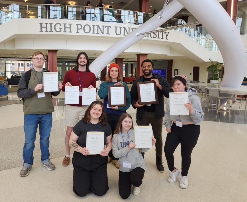 UNC Asheville students (back row from left) Jon Grunau, Jake Wilson, Elliot Jackson, Brandon Washington, Nelle Poehlman, (front row) Sarah Booth and Sydney Mason hold up the statewide awards received by The Blue Banner and Headwaters on Feb. 24.