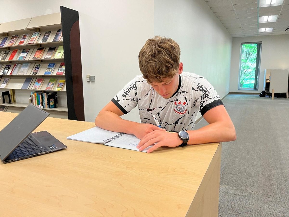 Charlie Wood using a pen and paper for his schoolwork.