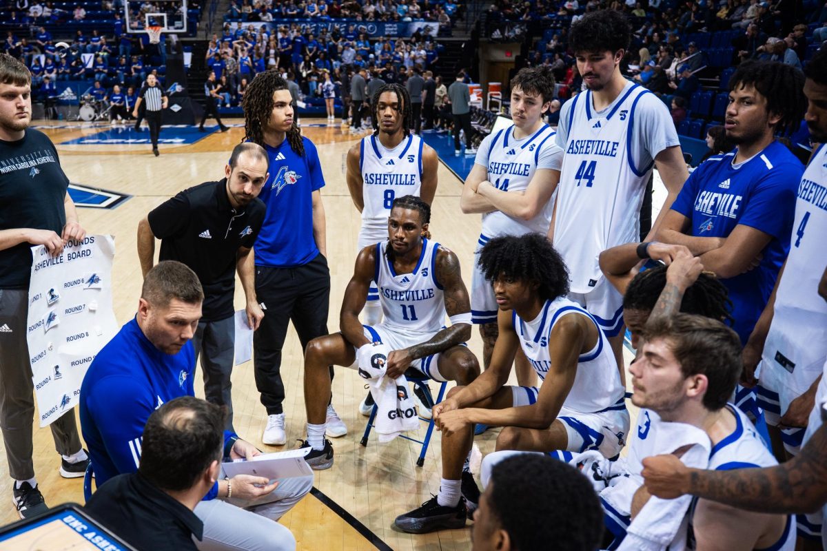 The UNCA Men's Basketball team huddles up around the coaches mid-game to figure out the next play.