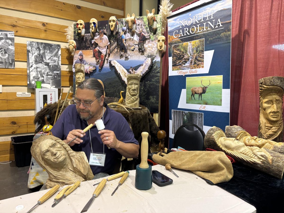 Woodworker Frank Dunn chisels into butternut at the NC Mountain State Fair, representing the Eastern Band of Cherokee.