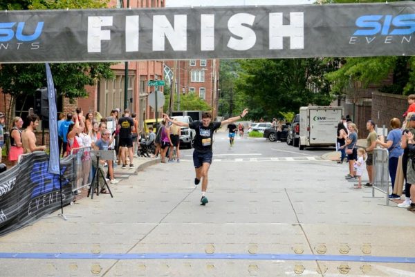 A runner on his way to finish the race as he celebrates with his fingers up.