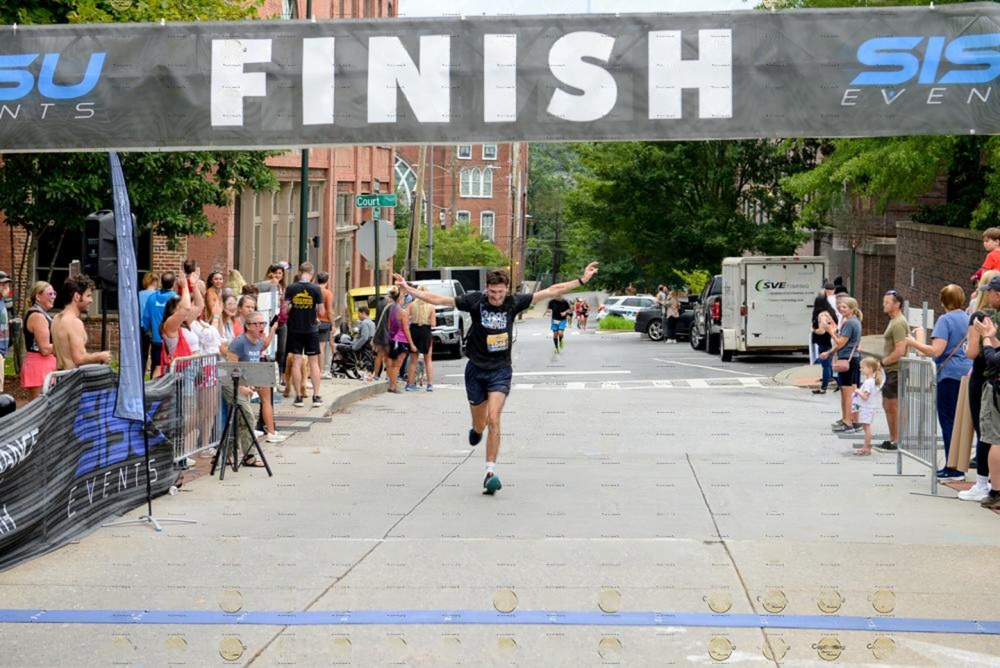 A runner on his way to finish the race as he celebrates with his fingers up.