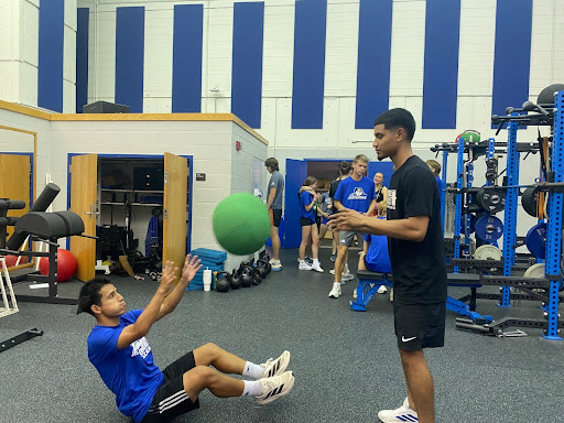 Assistant Strength and Conditioning Coach Jose Escalante-Justo assisting men’s soccer midfielder Xavier Alcantar with med ball throws.