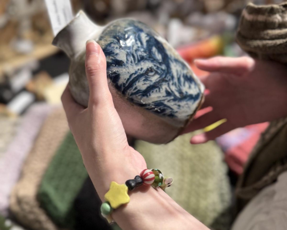 A shopper examines a student-made ceramic vase at UNC Asheville’s pottery sale.
