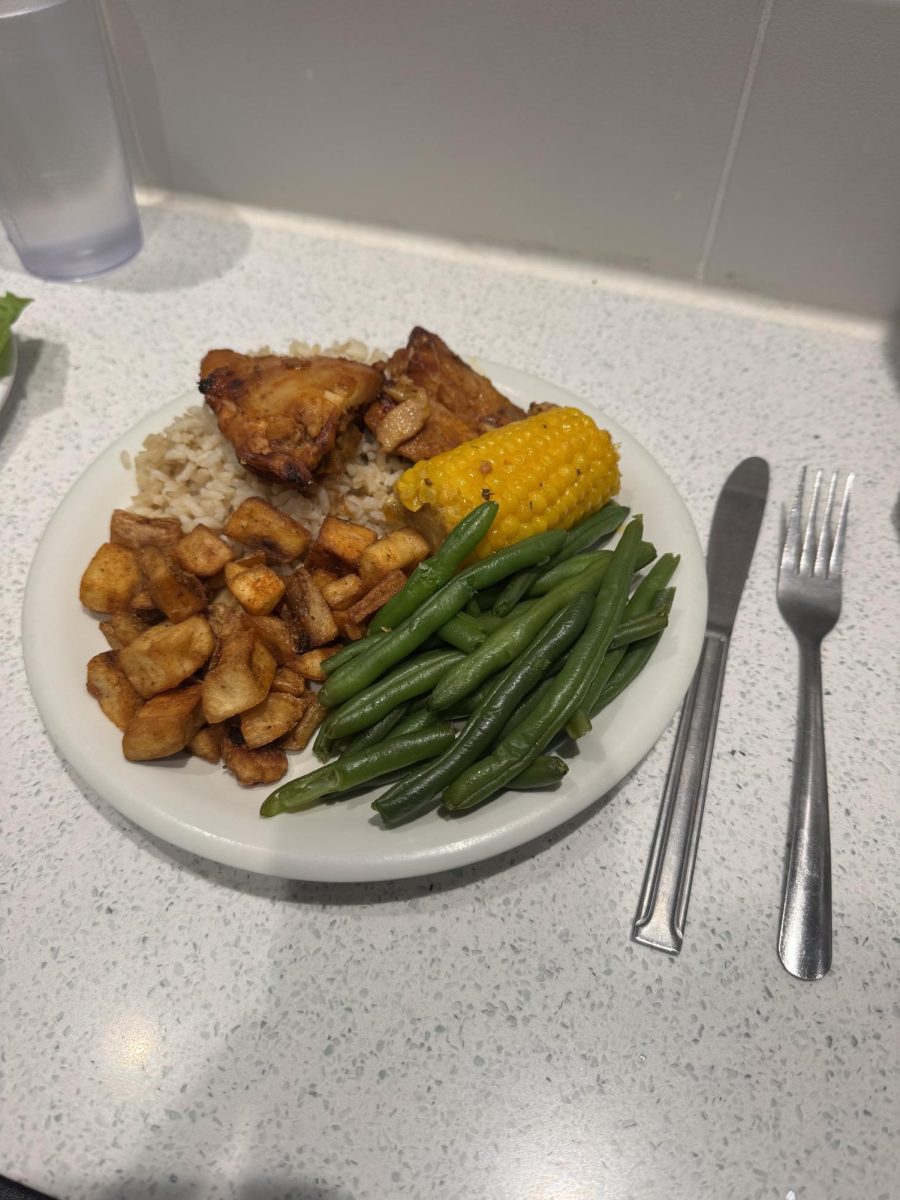 A hot meal option from the dining hall featuring roasted chicken, rice, seasoned potatoes, green beans and corn on the cob.
