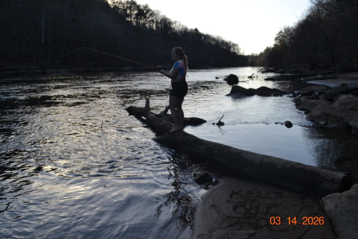 Rhi Sullens fishing off a log along the Hiwassee River, attempting to catch trout with no luck. 